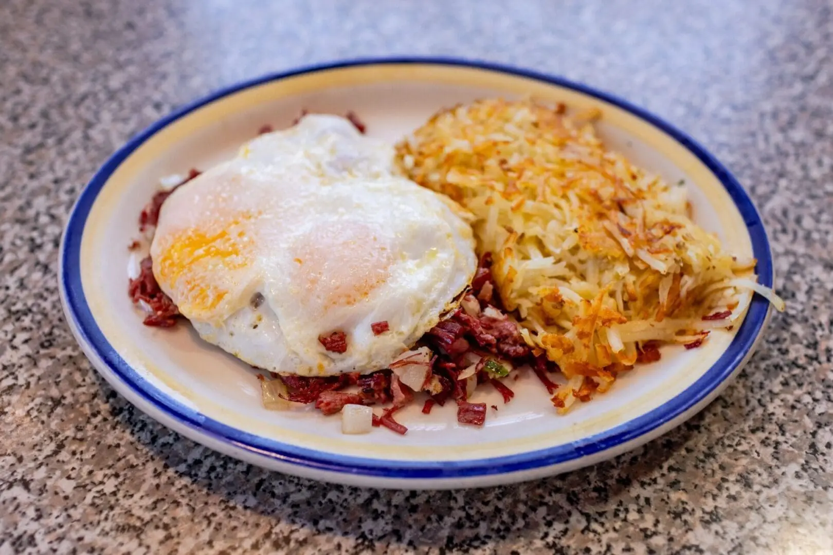 A plate of food with eggs and hash browns.