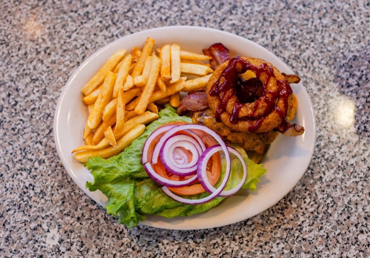 A plate of food with fries, onion rings and lettuce.