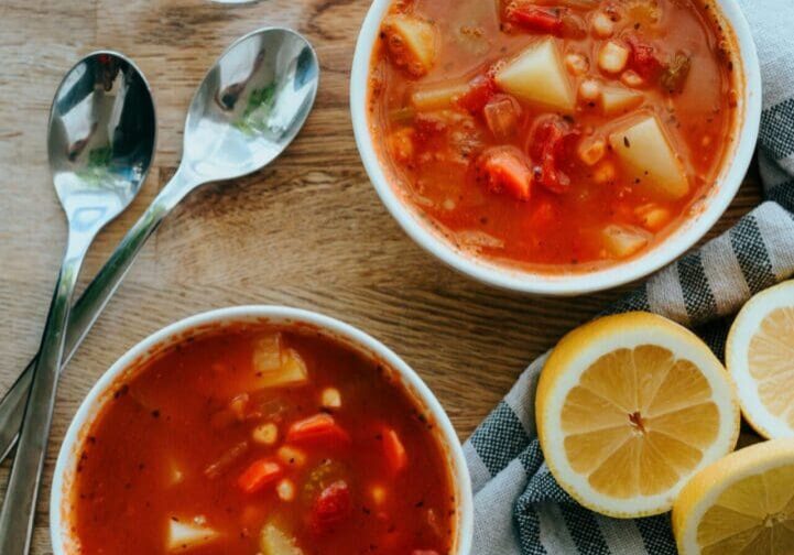 Two bowls of soup on a table with lemons.